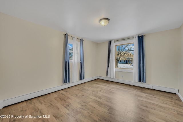 unfurnished room featuring a baseboard heating unit, a wealth of natural light, and light hardwood / wood-style flooring