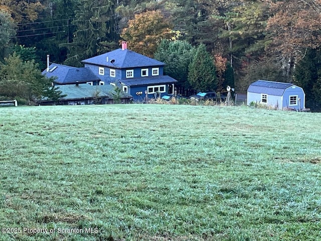 view of yard featuring a shed, an outdoor structure, and a view of trees