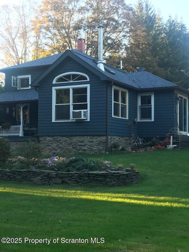 view of side of property with a yard, roof with shingles, and a chimney