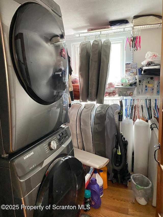 laundry room featuring laundry area, wood finished floors, and stacked washer and clothes dryer