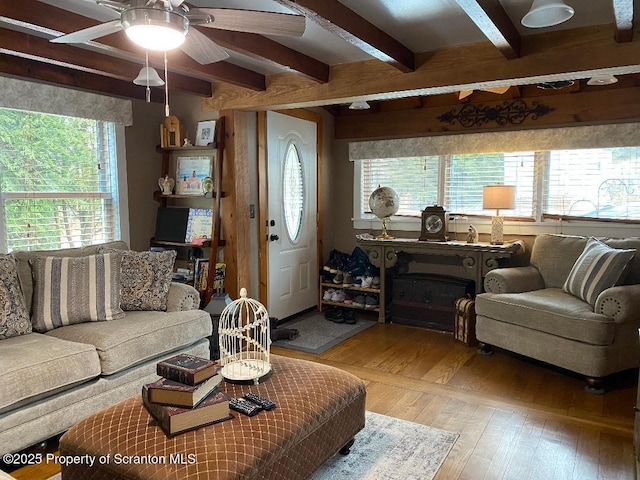 living area featuring beam ceiling, a ceiling fan, and wood finished floors