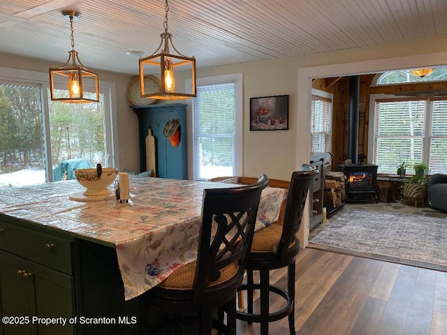 dining room featuring wood ceiling, a wood stove, a healthy amount of sunlight, and dark wood-style flooring