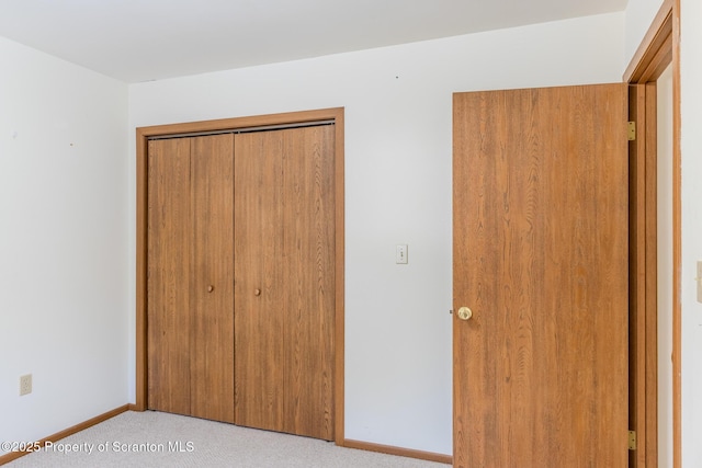 unfurnished bedroom featuring light carpet and a closet