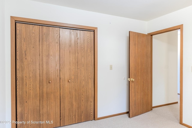 unfurnished bedroom with light colored carpet and a closet