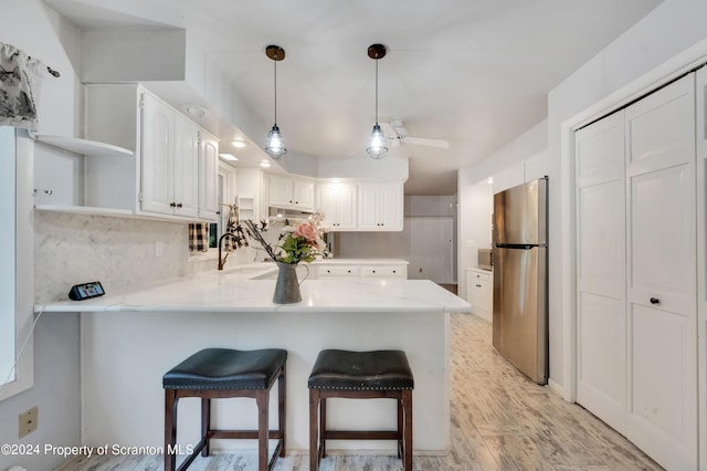 kitchen featuring kitchen peninsula, white cabinetry, and stainless steel refrigerator