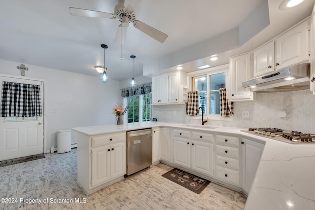 kitchen with sink, kitchen peninsula, pendant lighting, white cabinets, and appliances with stainless steel finishes