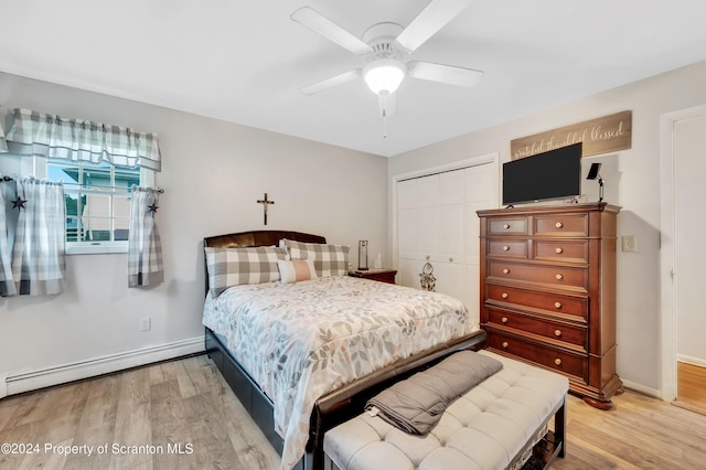 bedroom featuring wood-type flooring, a closet, a baseboard heating unit, and ceiling fan