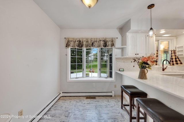 kitchen with pendant lighting, white cabinets, a kitchen breakfast bar, sink, and tasteful backsplash