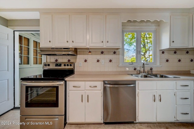 kitchen with stainless steel appliances, white cabinetry, sink, and tasteful backsplash