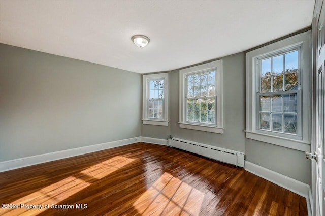 unfurnished room featuring dark wood-type flooring and a baseboard radiator