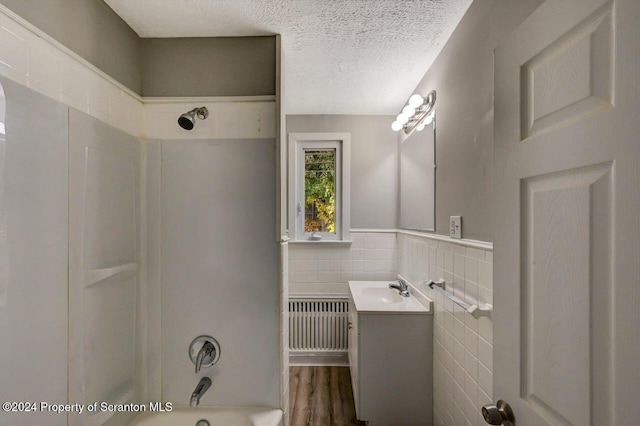 bathroom featuring hardwood / wood-style flooring, washtub / shower combination, tile walls, radiator heating unit, and vanity