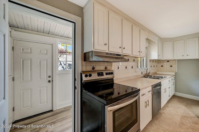 1319 Pine St, Scranton, PA 18510 - kitchen with stainless steel appliances, under cabinet range hood, tasteful backsplash, light countertops, and white cabinets