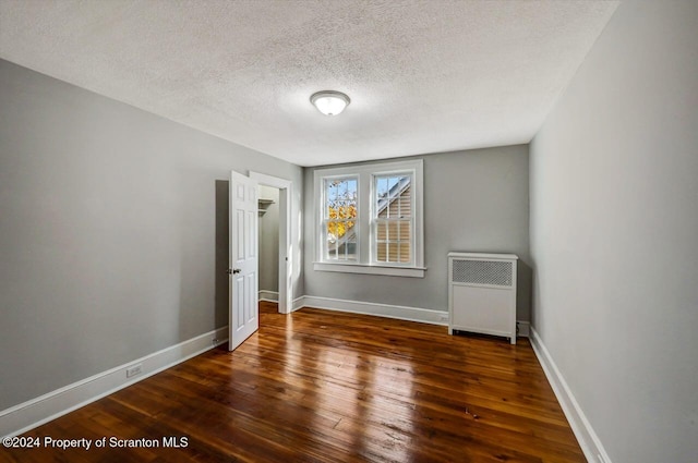 interior space featuring radiator heating unit, dark hardwood / wood-style flooring, and a textured ceiling