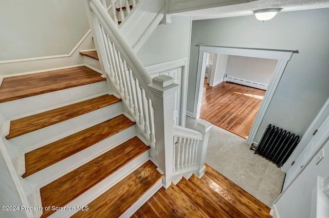 stairway with hardwood / wood-style flooring and baseboard heating