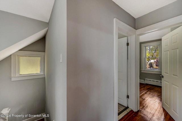 hall with dark wood-type flooring, lofted ceiling, and a baseboard heating unit