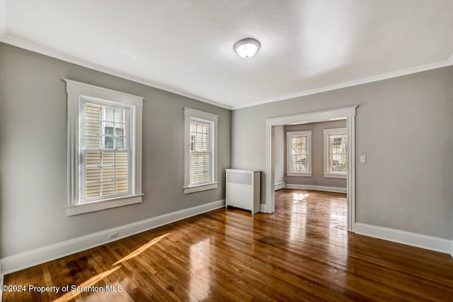 empty room featuring crown molding, dark hardwood / wood-style floors, and radiator heating unit