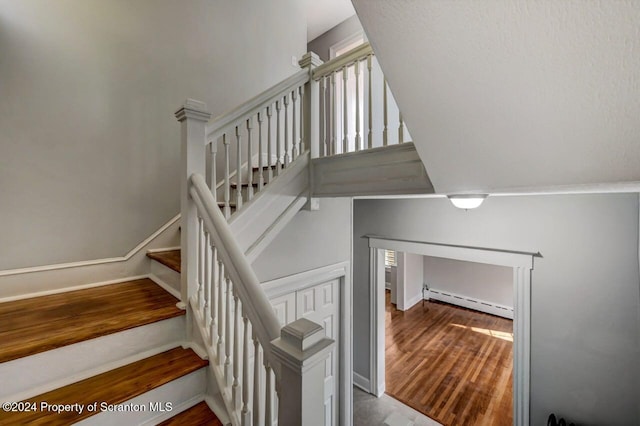 stairway featuring hardwood / wood-style floors and baseboard heating