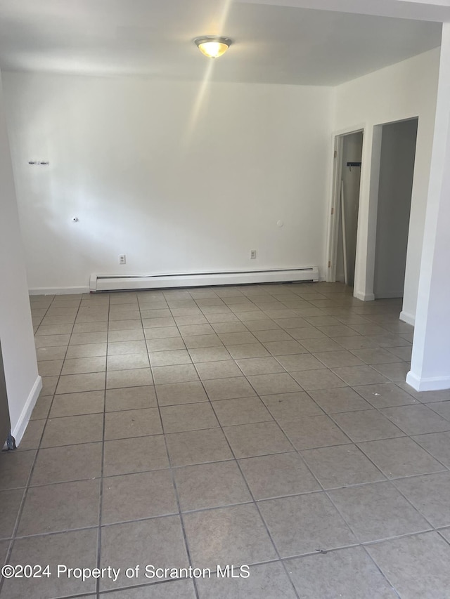 tiled empty room featuring a baseboard heating unit