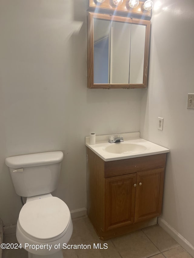 bathroom with toilet, tile patterned flooring, and vanity