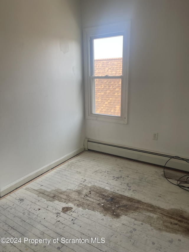 empty room with baseboard heating and light hardwood / wood-style flooring