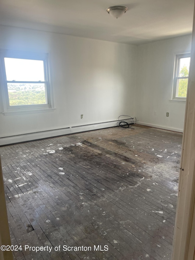 spare room featuring dark wood-type flooring and a baseboard heating unit