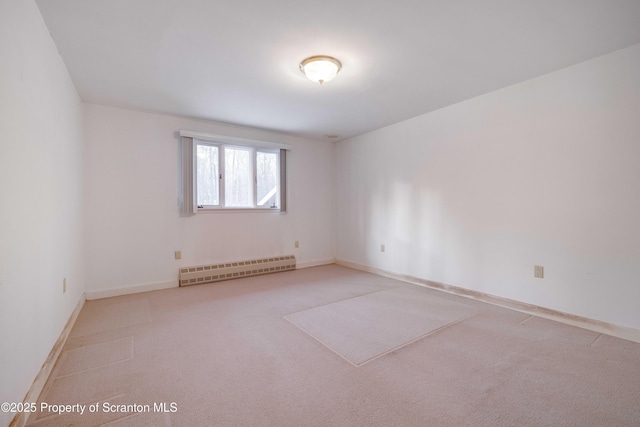 carpeted empty room featuring a baseboard heating unit