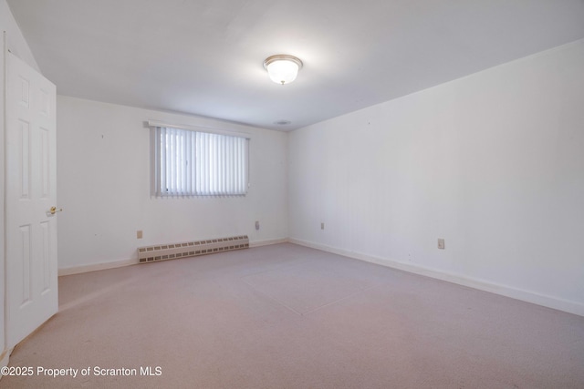 spare room featuring light carpet and a baseboard heating unit