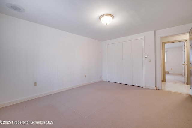 unfurnished bedroom with light colored carpet and a closet