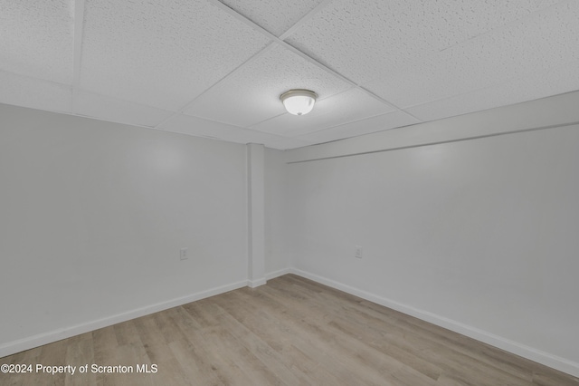 spare room featuring a paneled ceiling and light hardwood / wood-style flooring