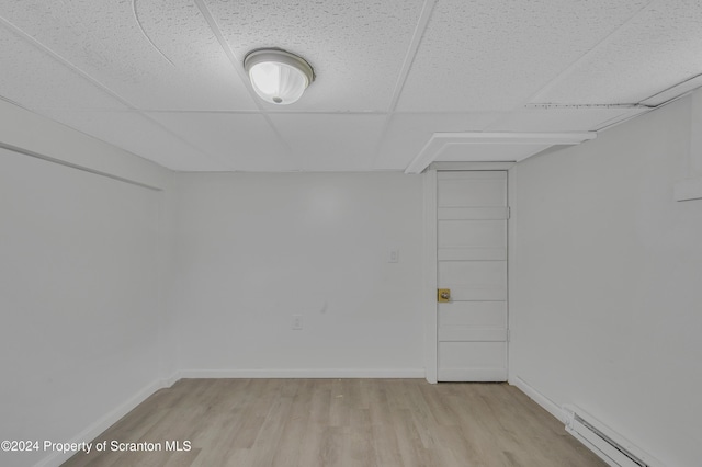 interior space featuring a drop ceiling, light wood-type flooring, and baseboard heating