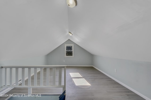 additional living space featuring vaulted ceiling and hardwood / wood-style flooring