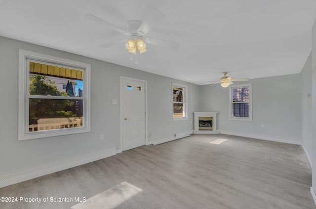 unfurnished living room featuring ceiling fan, light hardwood / wood-style floors, and a baseboard heating unit