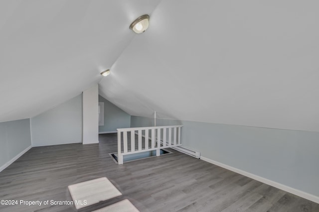 additional living space with hardwood / wood-style floors and vaulted ceiling