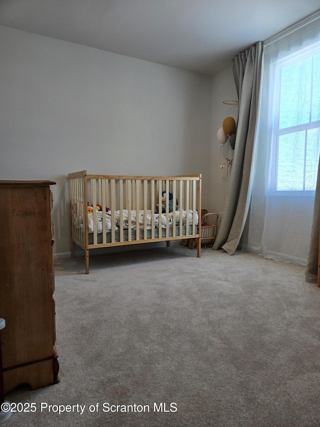 unfurnished bedroom with a nursery area and carpet flooring