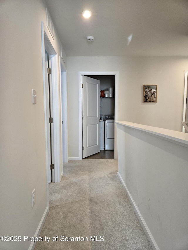 hallway with washing machine and dryer and light carpet