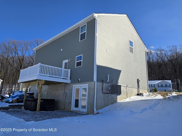 snow covered property featuring a wooden deck and central AC