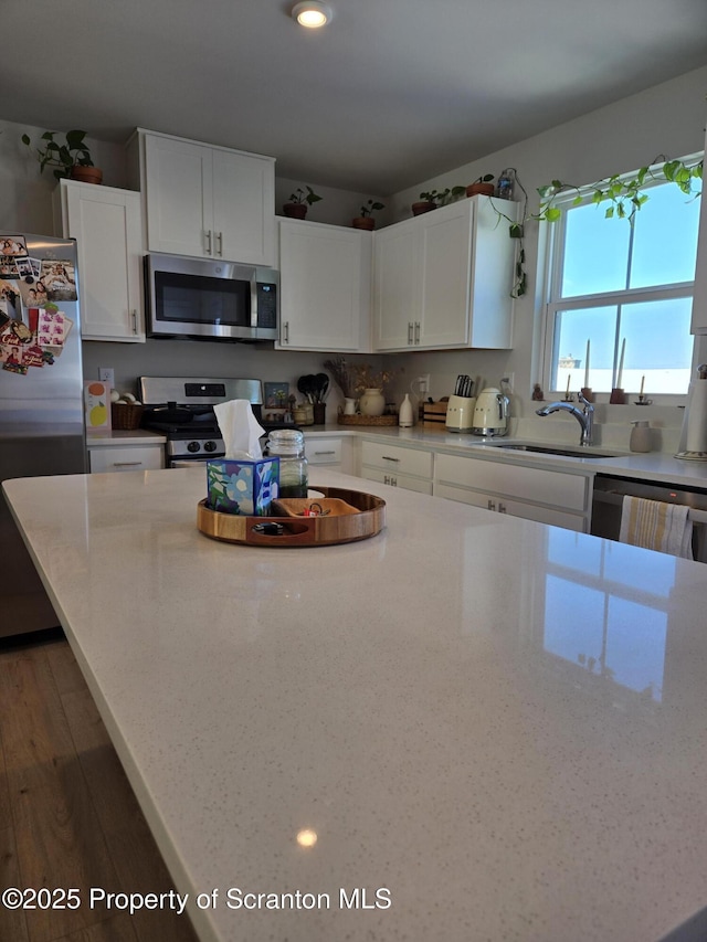 kitchen featuring white cabinetry, stainless steel appliances, light stone countertops, and sink