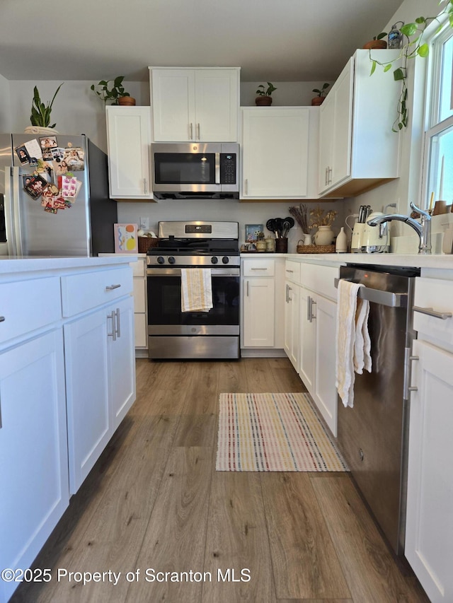 kitchen featuring appliances with stainless steel finishes, sink, hardwood / wood-style floors, and white cabinets