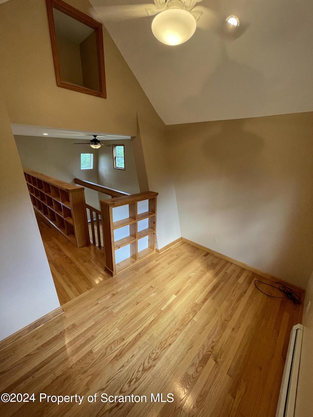 additional living space featuring ceiling fan, wood-type flooring, lofted ceiling, and a baseboard heating unit