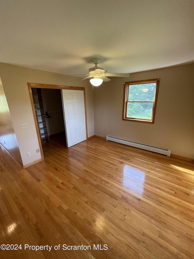 unfurnished bedroom featuring ceiling fan, a closet, a baseboard radiator, and light hardwood / wood-style flooring