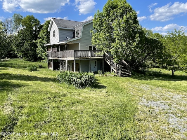 back of house featuring a deck and a lawn