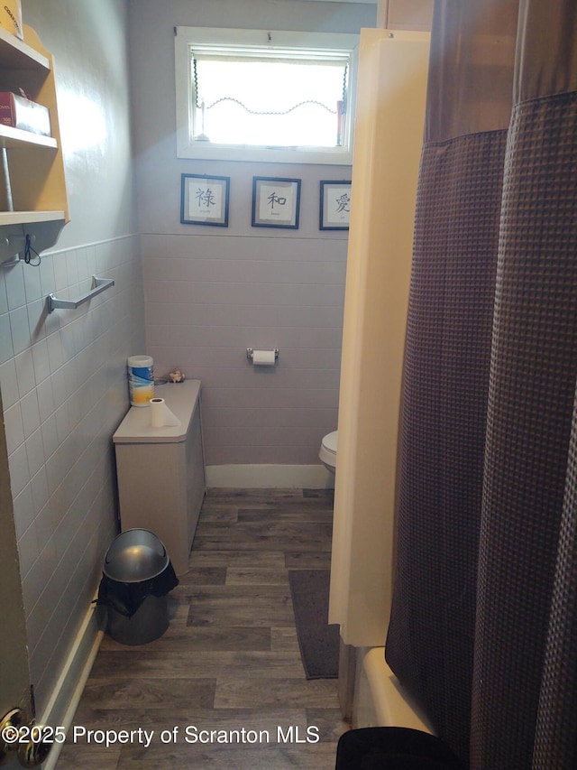 bathroom with tile walls, a shower with curtain, wood-type flooring, and toilet