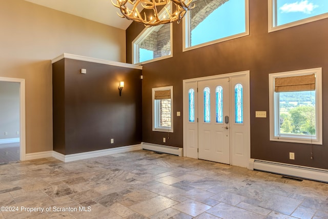 entrance foyer featuring a towering ceiling, a chandelier, and a baseboard heating unit