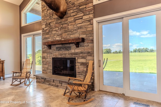 living room with a baseboard heating unit, a rural view, a fireplace, and french doors