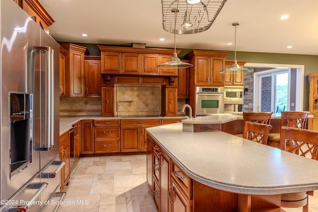 kitchen featuring a breakfast bar area, pendant lighting, an island with sink, and stainless steel appliances