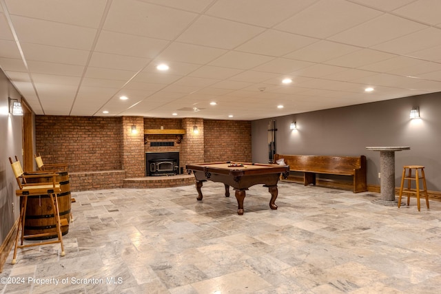 game room featuring a wood stove, a drop ceiling, brick wall, and pool table