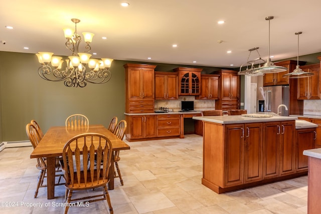 kitchen featuring hanging light fixtures, decorative backsplash, an island with sink, high quality fridge, and a notable chandelier