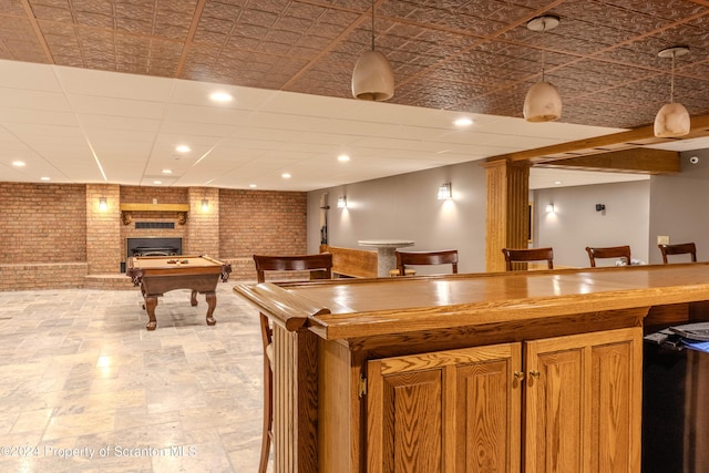 kitchen featuring decorative light fixtures, brick wall, a fireplace, and billiards