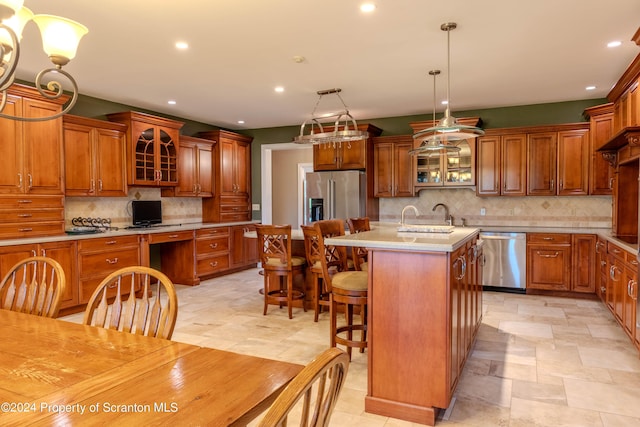 kitchen with stainless steel appliances, sink, decorative light fixtures, a breakfast bar area, and an island with sink