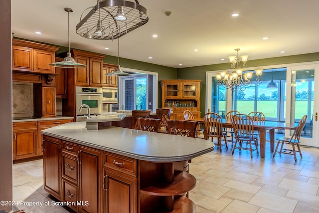 kitchen featuring a kitchen island with sink, hanging light fixtures, appliances with stainless steel finishes, a breakfast bar area, and a chandelier